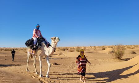 Frau reitet auf Kamel durch die Wüste