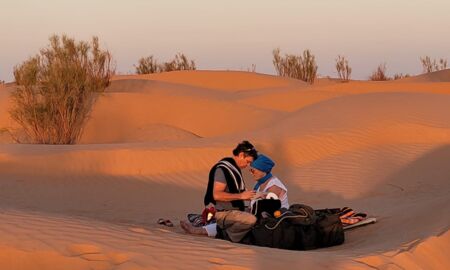 Mann und Frau sitzen sich gegenüber am Boden in der Wüste